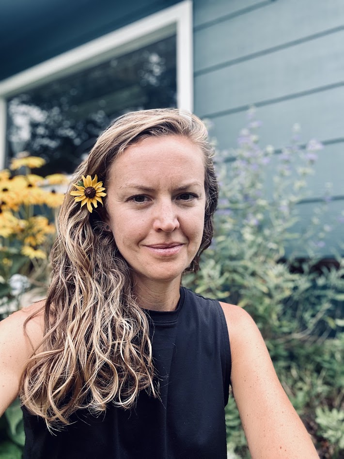 Emily Reeves smiles at camera with yellow flower in her hair